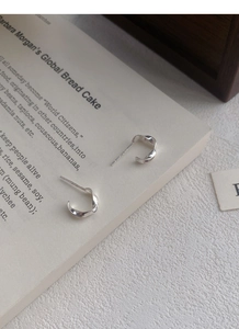 Detail of S999 sterling silver Mobius C-shaped stud earrings on an open book page