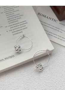 Detail of silver beaded hoop earrings placed on a romantic book page setting