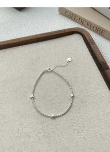 Close-up of S925 sterling silver star bracelet with textured beads on a beige fabric tray