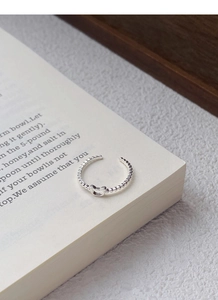 Detailed view of silver U-shaped bear ring with bubble texture on a white book page