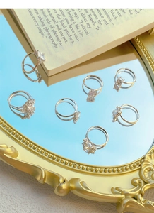 Set of seven silver adjustable rings with various zircon cuts on a luxury mirror surface
