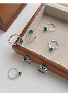 Macro view of six S925 silver adjustable rings with emerald-cut green zircon gemstones