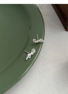 Detailed view of S999 sterling silver bow earrings with fine brushed metal texture finish