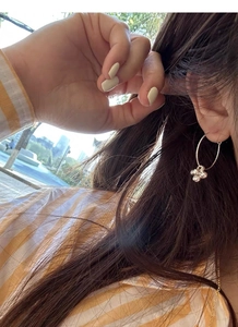 Detailed view of silver hoop earrings with floral charms worn for a stylish daily look