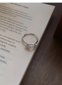 Macro shot of a sparkling square-cut zircon silver ring resting on a vintage book