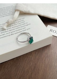 Detail of S925 sterling silver ring with emerald oval gemstone on an open vintage book