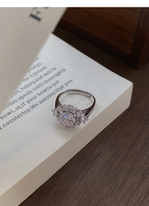 Detail of S925 silver halo ring with zircon flower design placed on an open book