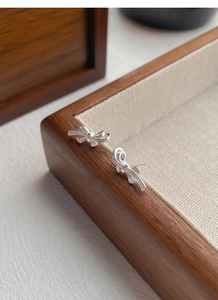 Detailed view of S999 sterling silver bow earrings with brushed metal texture