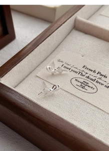 Macro shot of silver bow stud earrings with intricate ribbon knot detail on fabric
