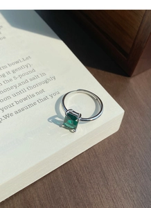 Macro shot of S925 silver ring with emerald cut green zircon on vintage book pages