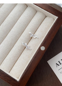 Close-up of S999 sterling silver bow earrings with detailed brushed metal texture