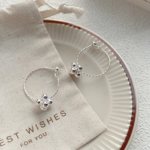 Elegant S925 sterling silver twist hoop earrings with four small silver beads on a tray