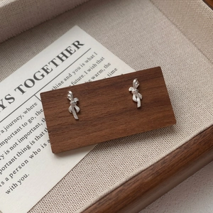 Minimalist S999 sterling silver bow knot stud earrings on a wooden display block