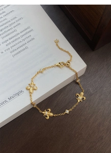 Dettaglio di un bracciale vintage dorato con fiori di giglio e ciondoli a stella