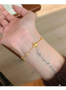 Dettaglio macro di un bracciale a giglio dorato con zirconi brillanti su un polso