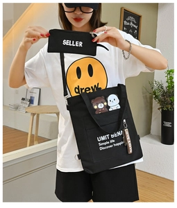 Close-up of black canvas tote bag with adjustable strap and cute bear charm accessory