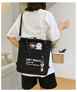 Detail of black canvas tote bag with cartoon animal pockets and bear charm accessory
