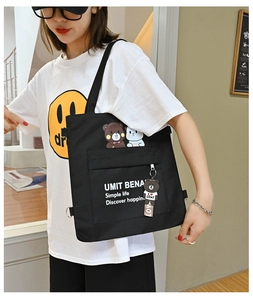 Close-up of black canvas tote bag with cartoon bear print and plush charm for students