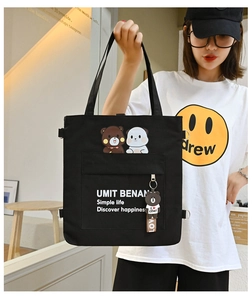 Detail of black canvas tote bag featuring bear print and matching plush keychain charm