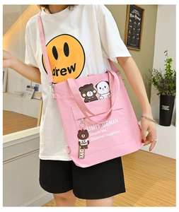 Pink canvas tote bag with cartoon bears and adjustable strap shown on model in detail