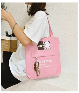 Detail of pink canvas crossbody bag with cute bear print and decorative love strap