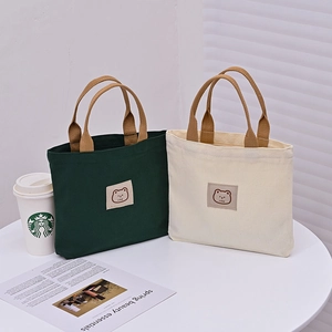 Minimalist canvas tote bags with bear patch and brown handles in green and beige colors