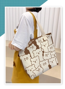 Detailed shot of large cream canvas tote bag with bear print worn with yellow overalls