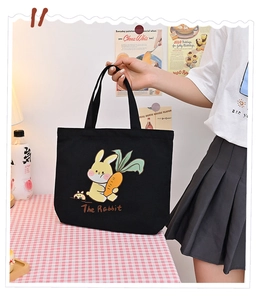 Detailed shot of a cute cartoon rabbit black canvas tote bag being held by hand