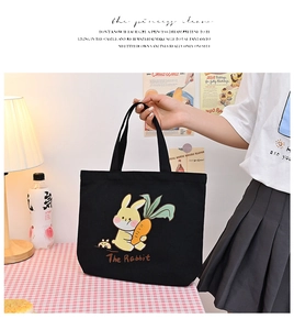 Detailed close-up of black canvas tote bag featuring cute yellow rabbit illustration