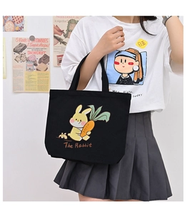Close-up of a stylish black canvas tote bag featuring a cute cartoon rabbit and carrot