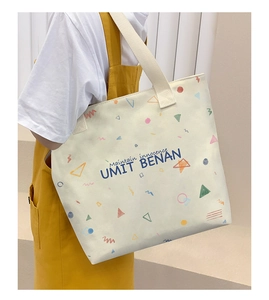 Detailed side view of off-white canvas tote bag with geometric prints worn by model