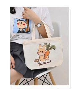 Close-up of beige canvas handbag with cute rabbit illustration held by a model