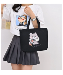 Detailed view of black canvas tote bag featuring cute cartoon bear print and The Bear text