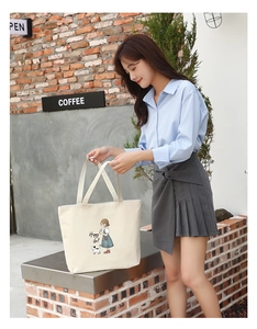 Detail of beige canvas tote bag with Happy Girl illustration in an outdoor cafe setting