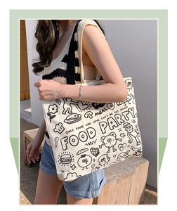 Detail of canvas tote bag featuring cute cartoon food graffiti and text print in outdoor light
