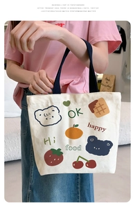 Close-up of small canvas lunch tote featuring cute cartoon bear and fruit illustrations