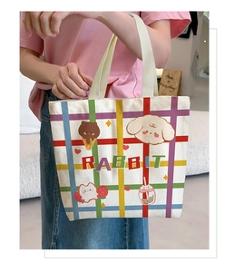 Close-up of a white canvas tote bag with colorful plaid patterns and cute rabbit prints