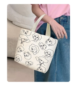 Detailed view of white canvas tote bag featuring minimalist black line art woman portrait