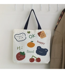 Detail of white canvas tote bag with colorful bear and fruit illustrations and blue handle