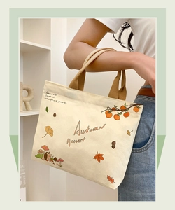 Close-up of beige canvas bag with autumn hedgehog illustration and brown strap