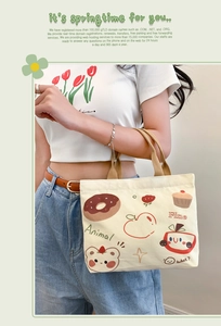 Detail of off-white canvas tote bag with cute cartoon illustrations and brown woven handles
