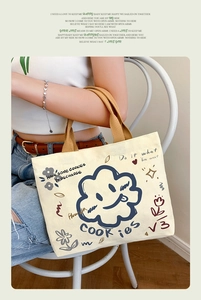 Detail of canvas tote bag with cartoon cloud and cookies text held by a model