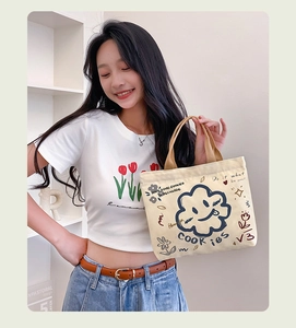 Detailed view of canvas tote bag featuring cute cartoon cookie prints and webbing handles