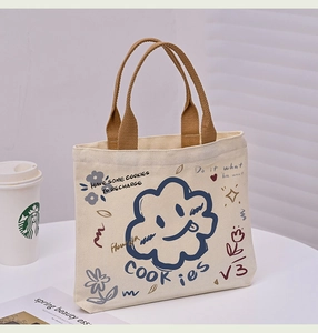 Detail of canvas tote bag with blue cloud smile print and brown top handles