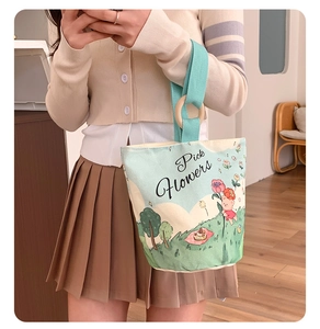 Close-up of canvas bucket bag featuring a cartoon bear print and wooden ring handle