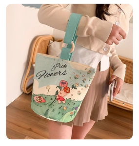 Detail of canvas tote bag featuring bear illustration and mint green straps with wood rings