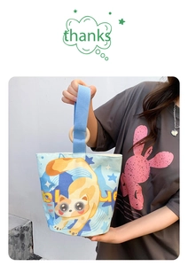 Detail of light blue canvas bucket bag featuring cartoon cat illustration and wood ring handles