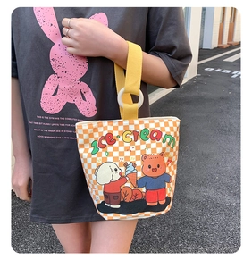 Detail of orange checkered canvas tote bag featuring cute cartoon bear and dog illustration