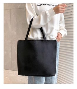 Detail of a large black canvas tote bag with long straps for versatile daily carrying