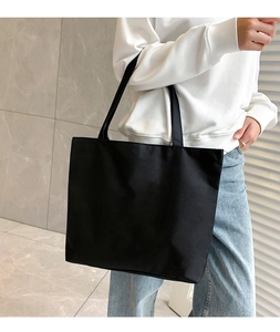 Detail of a black minimalist canvas tote bag showing the high-density nylon texture and strap